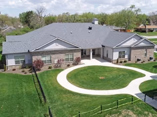 A single-story senior living home with a circular driveway and manicured lawn.