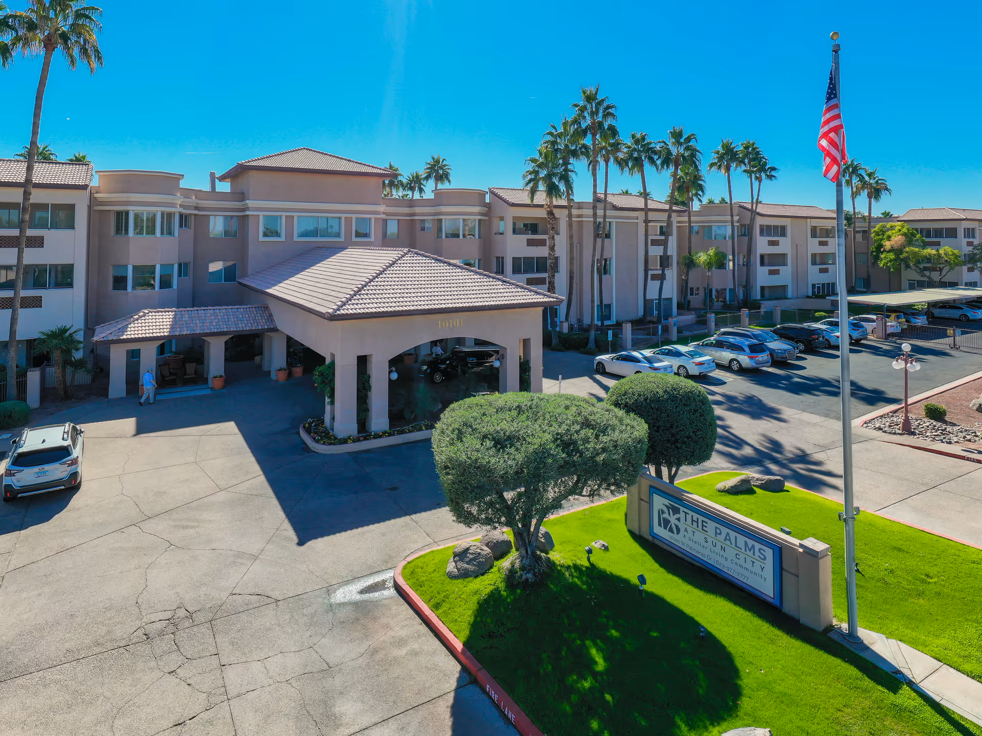 A multi-story assisted living facility, The Palms at Sun City, with porte-cochère entrance and palm trees.
