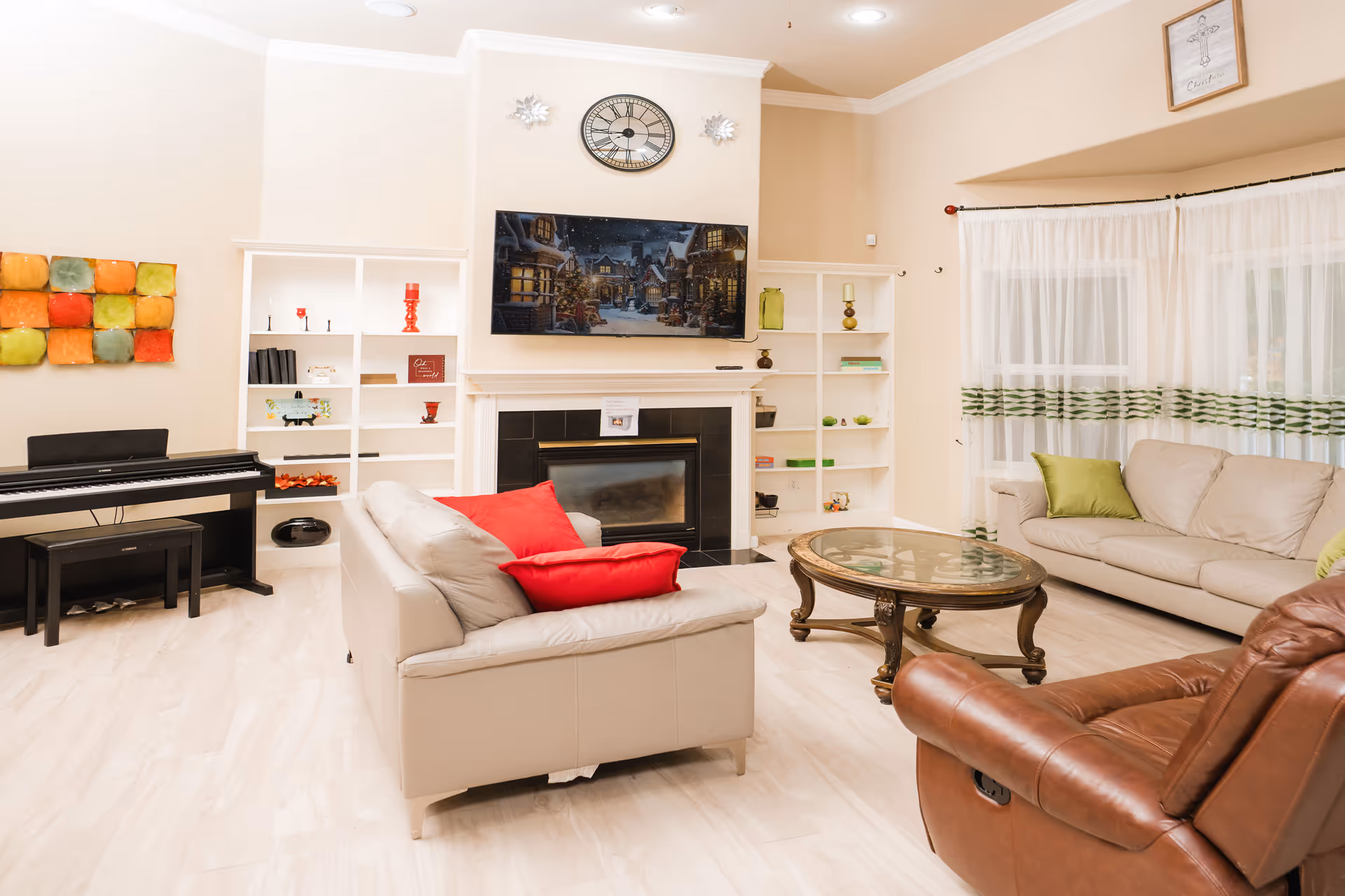 Bright living room in a senior facility with sofa, fireplace, shelves, and a piano.