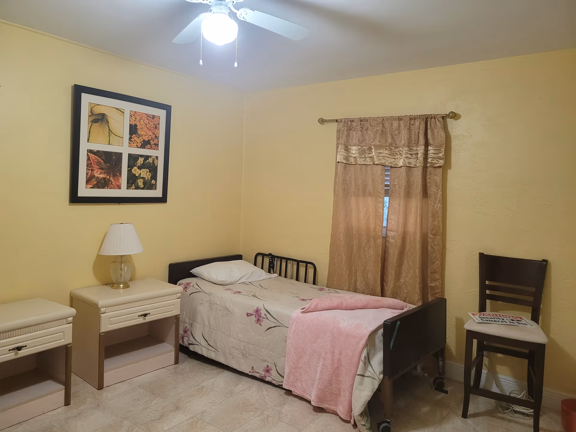 Cozy bedroom in a senior living facility with a bed, nightstand, lamp, and curtains.
