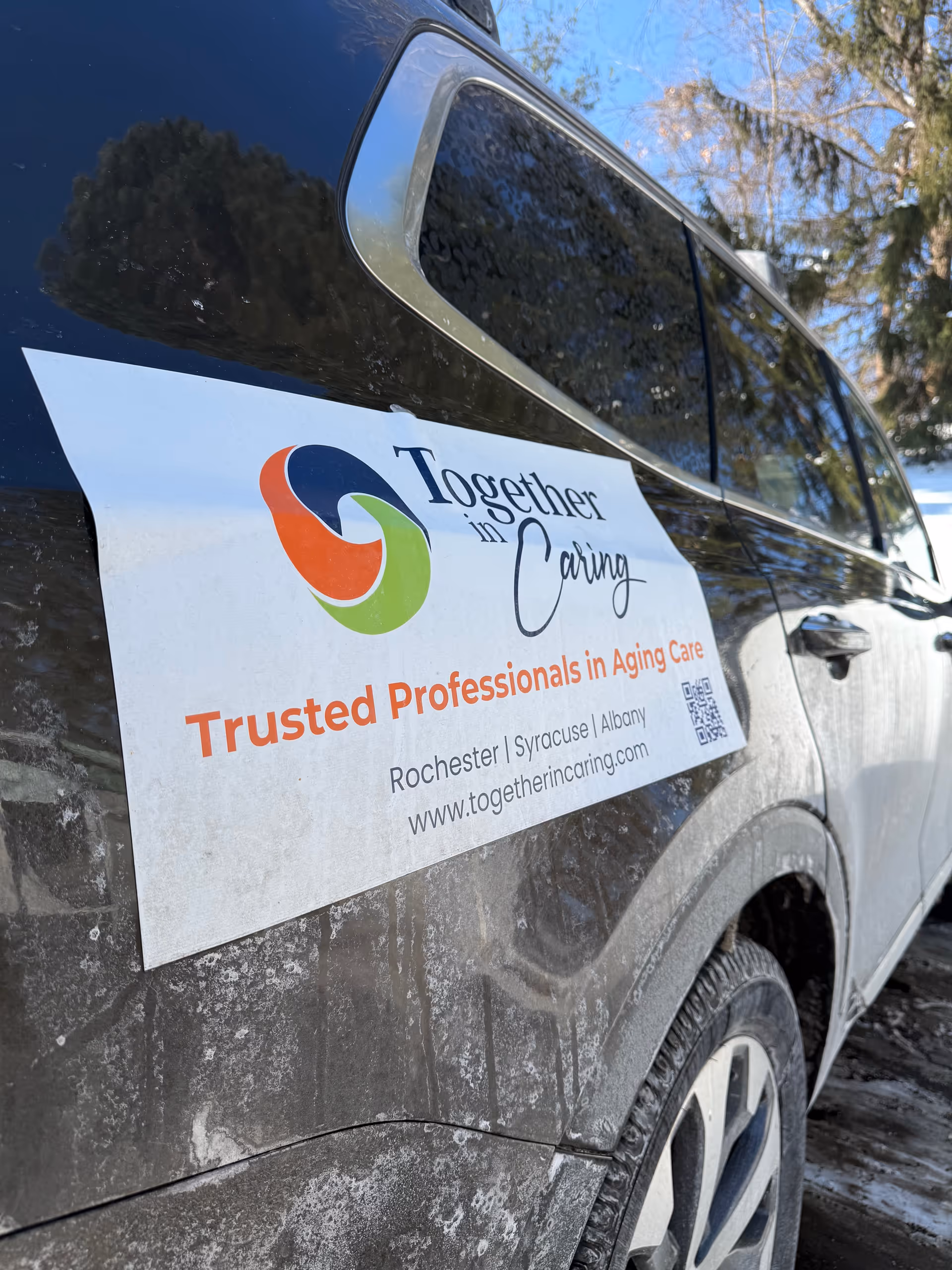 Dirt-splattered vehicle displaying Together in Caring branding on the door.