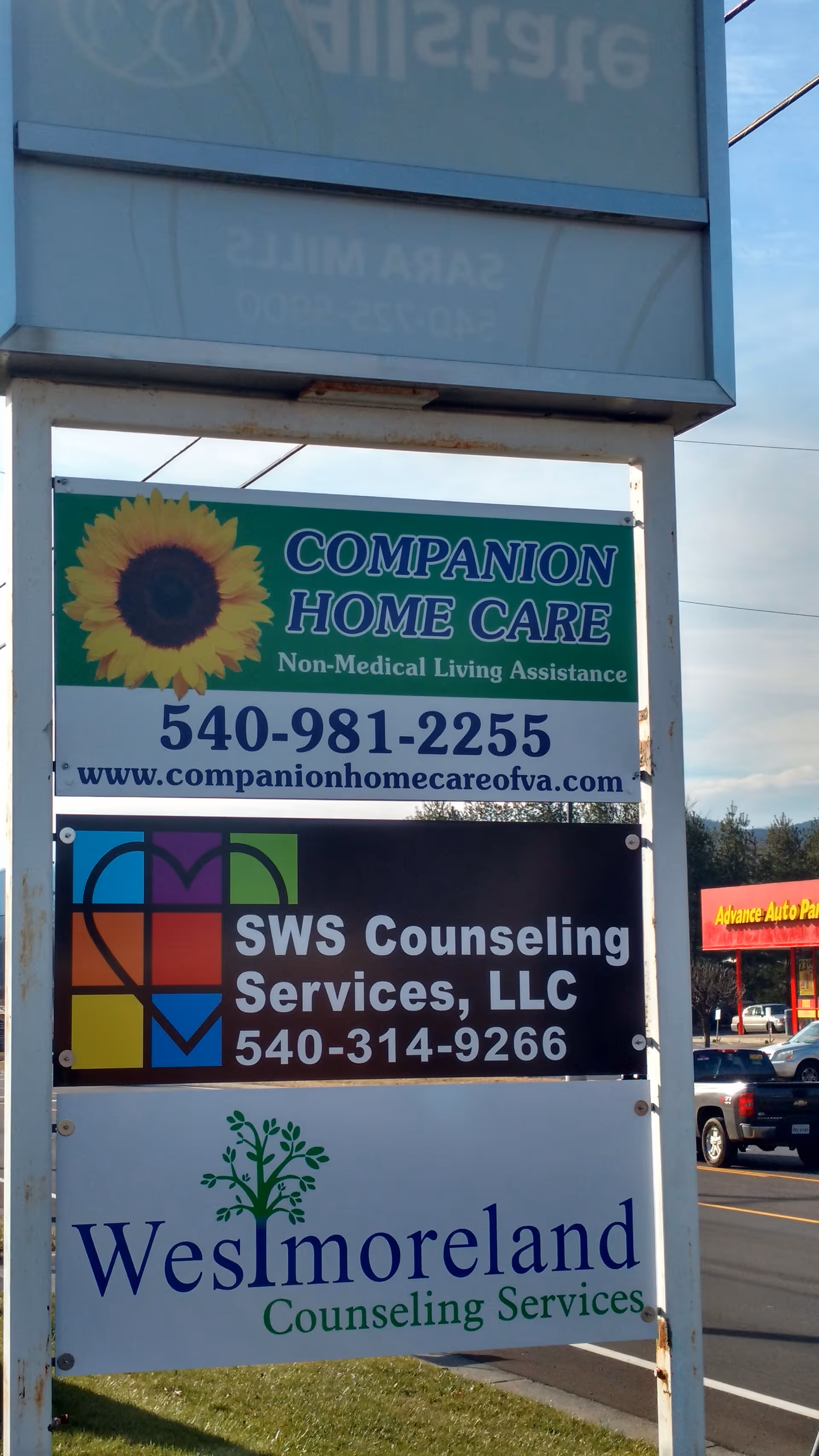Outdoor signboard featuring Companion Home Care and other business signs by the road