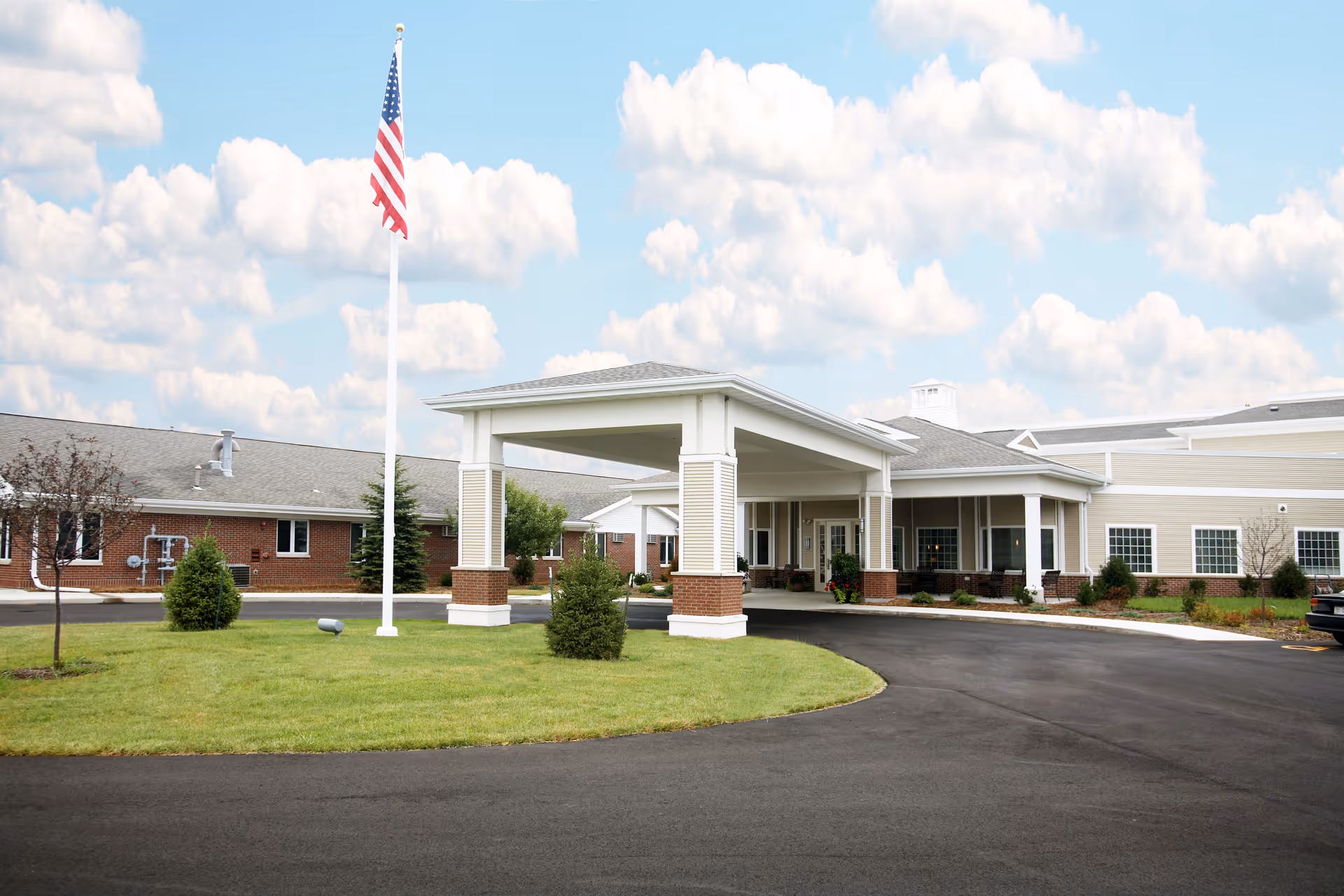 Exterior view of Valley VNA Senior Care facility with porte-cochère and flagpole.