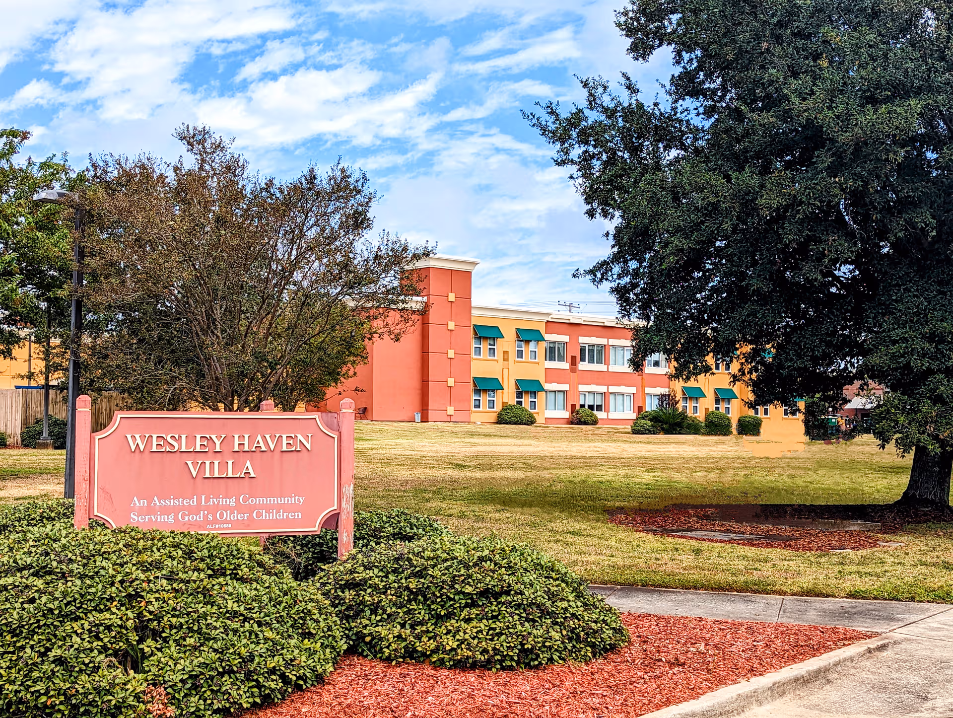Front view of Wesley Haven Villa with pink sign and colorful building exterior.