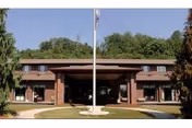 Front exterior of Fort Shelby Manor showing brick entrance, flagpole, and trees.