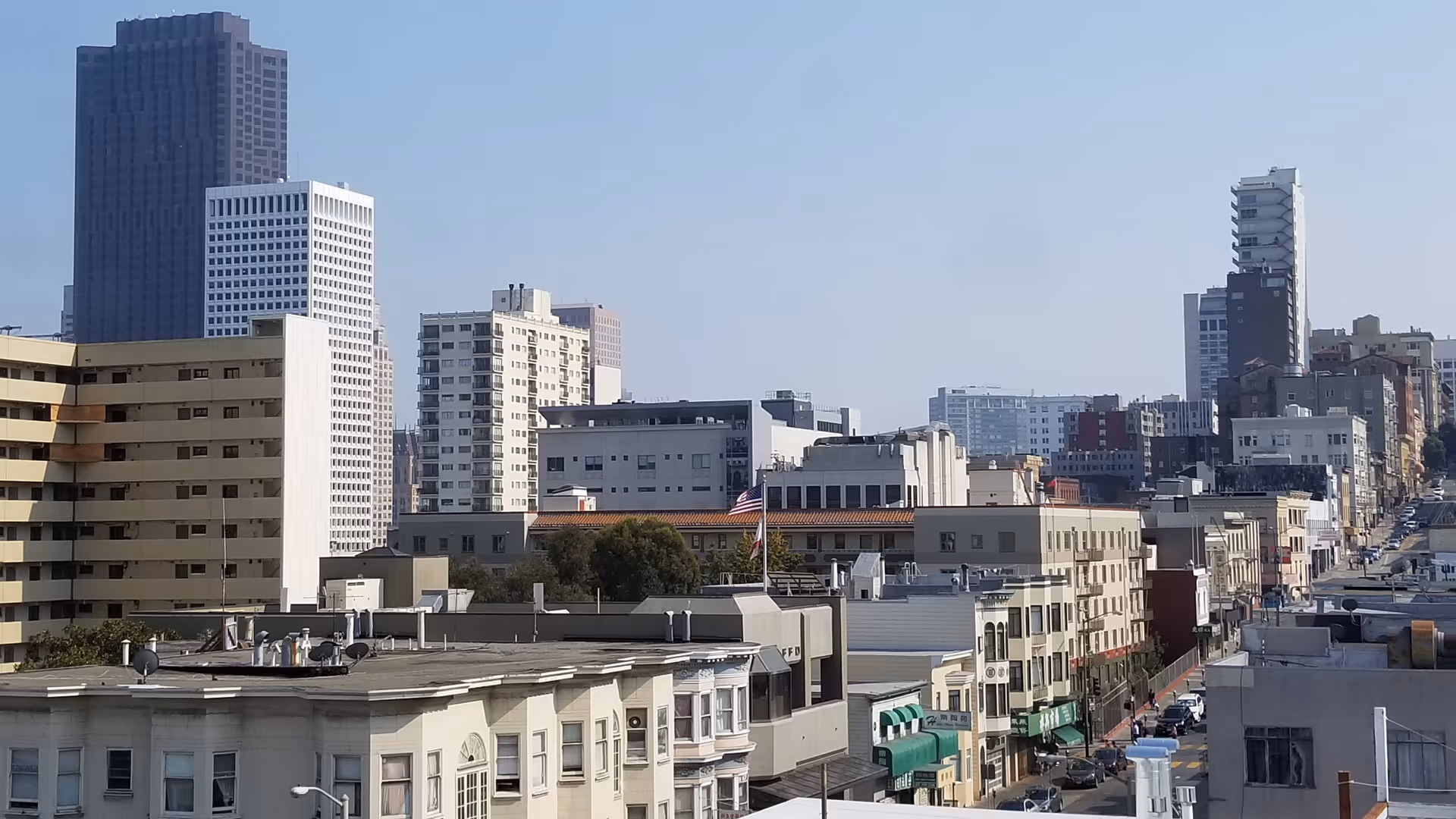 City street view with numerous mid-rise buildings under a clear blue sky.