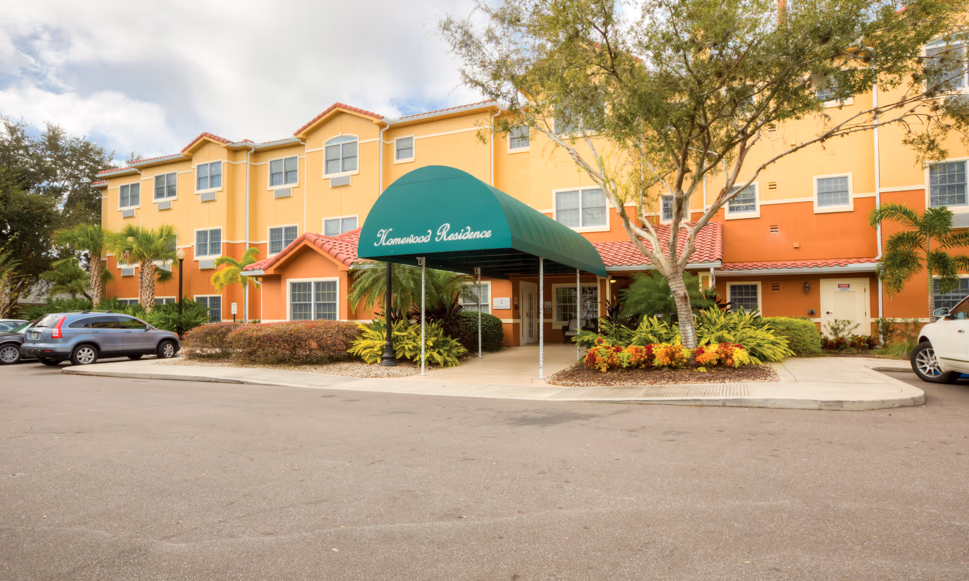 Exterior view of a colorful senior living building with a green entrance canopy.