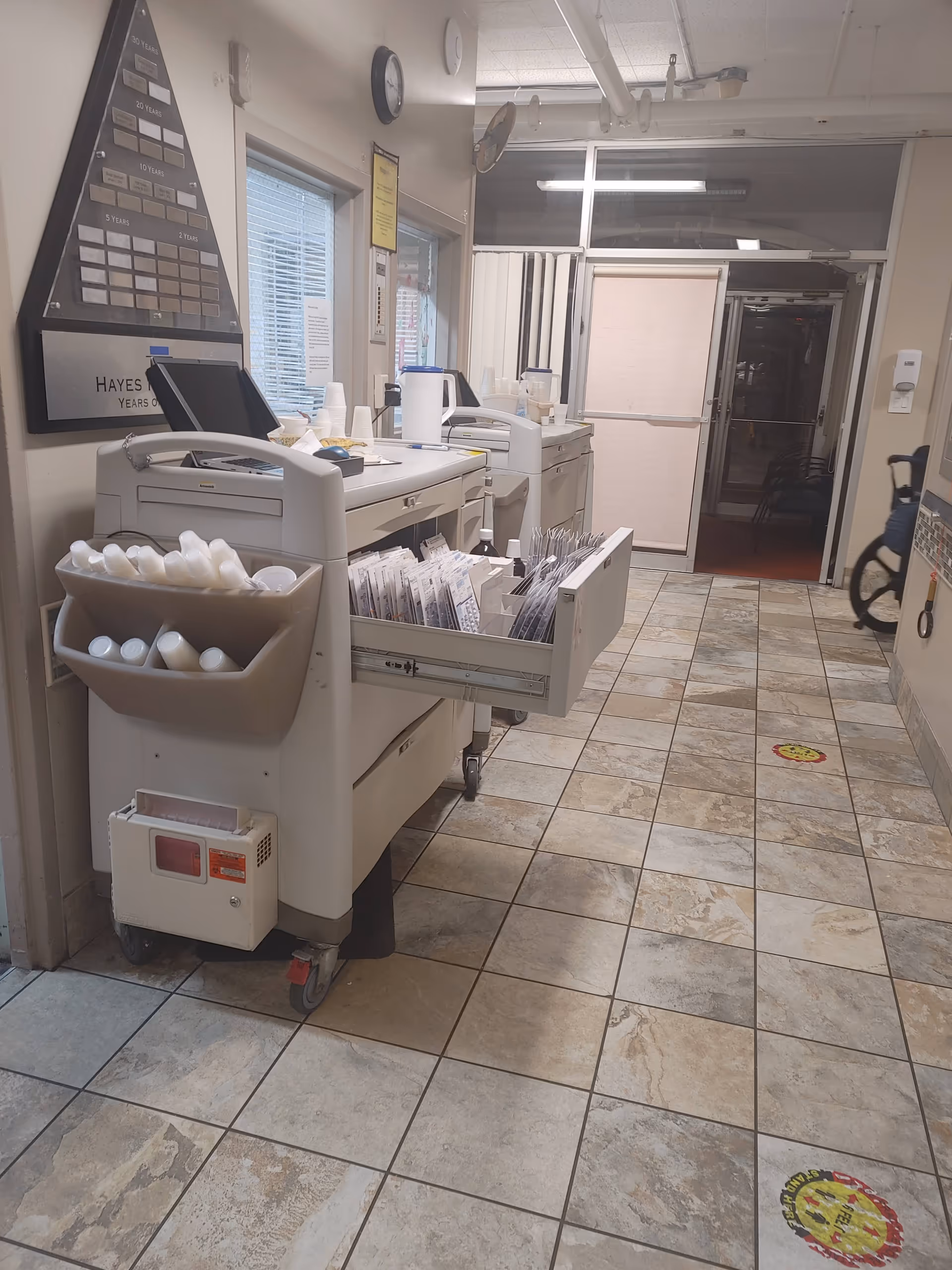 Interior corridor featuring printers, a supply cart, and files.
