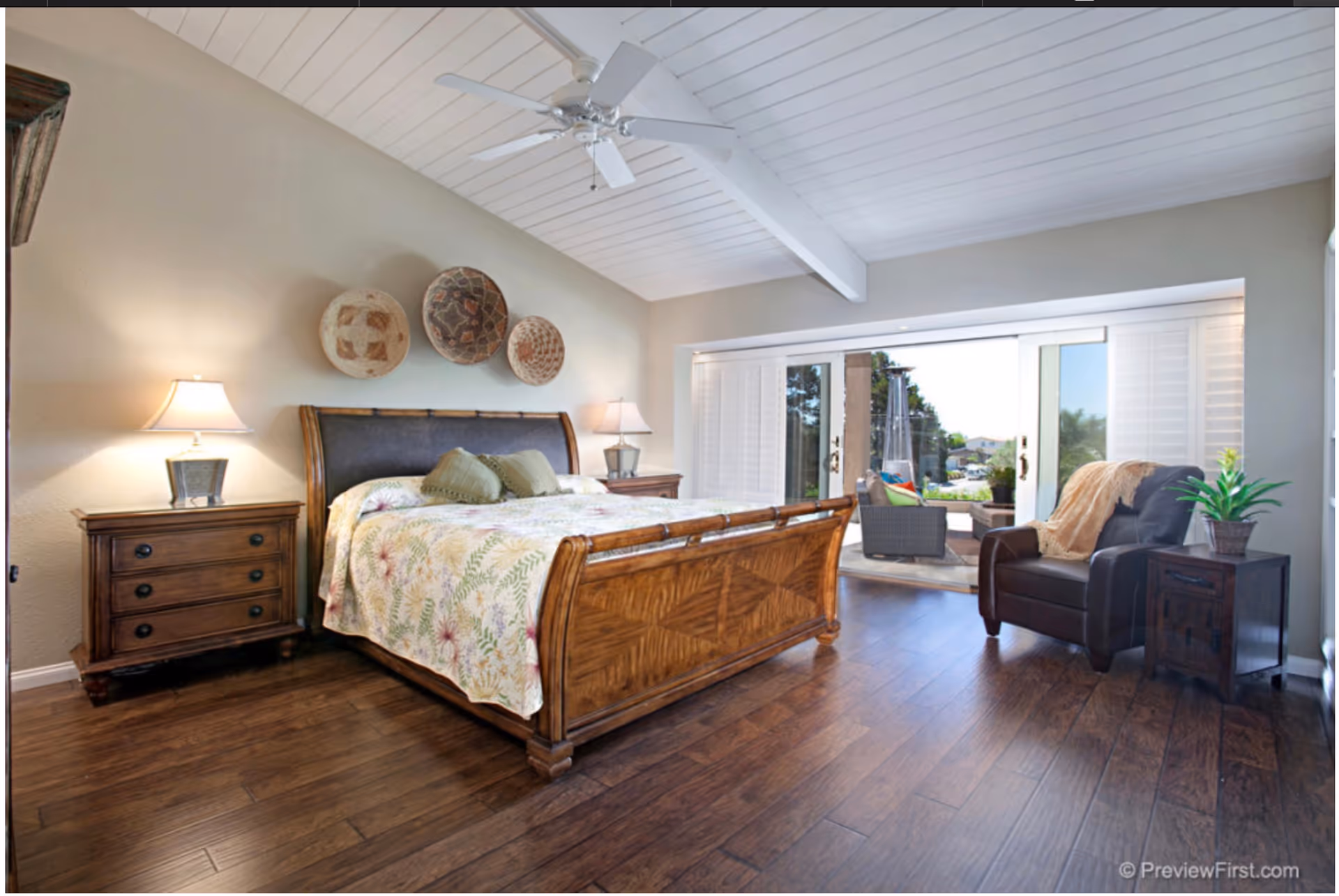 A spacious bedroom with a wooden bed, nightstands, and a view of an outdoor patio.