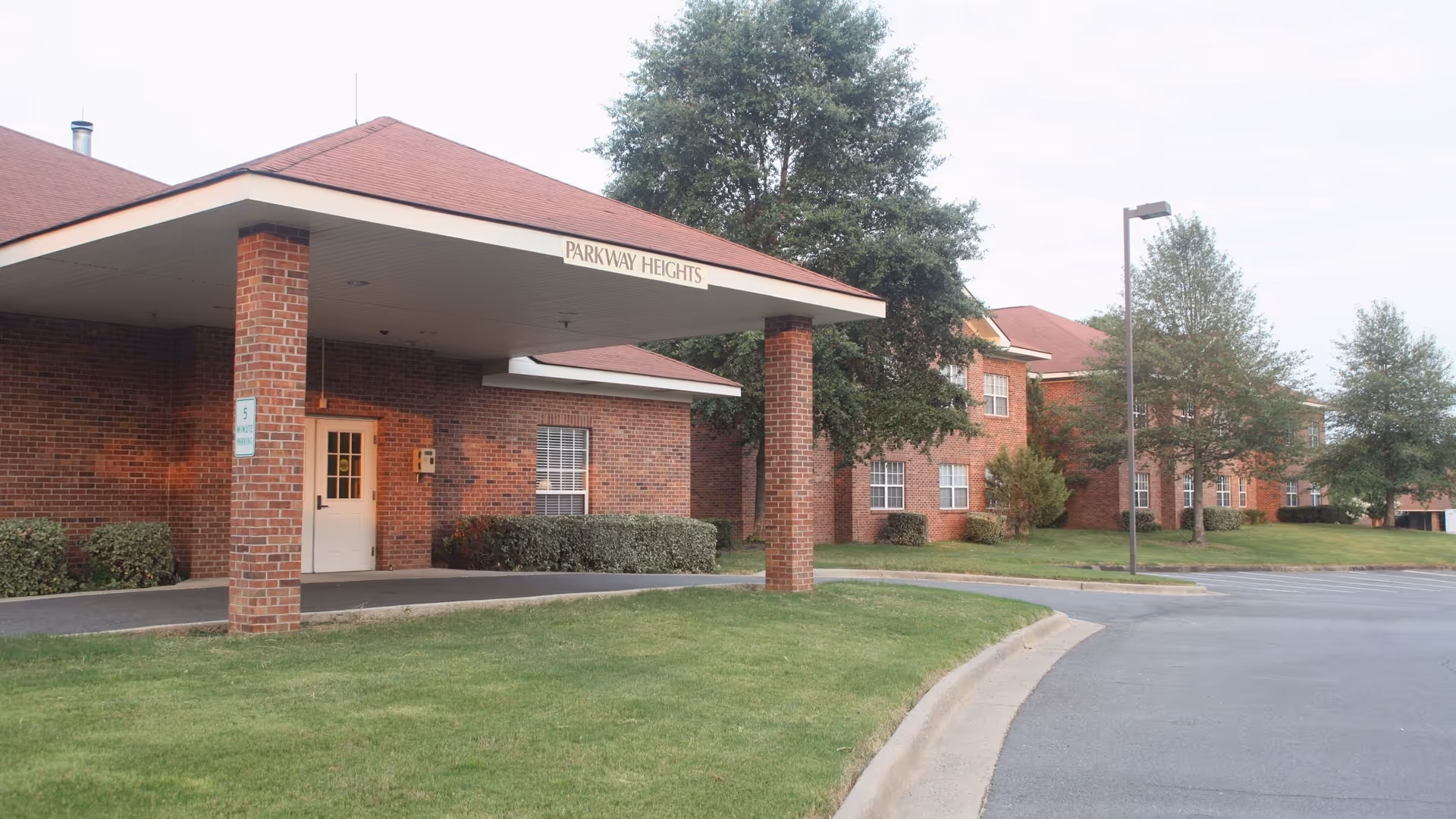 Brick senior living facility with a covered entrance, sign reading Parkway Heights, and a curved driveway.