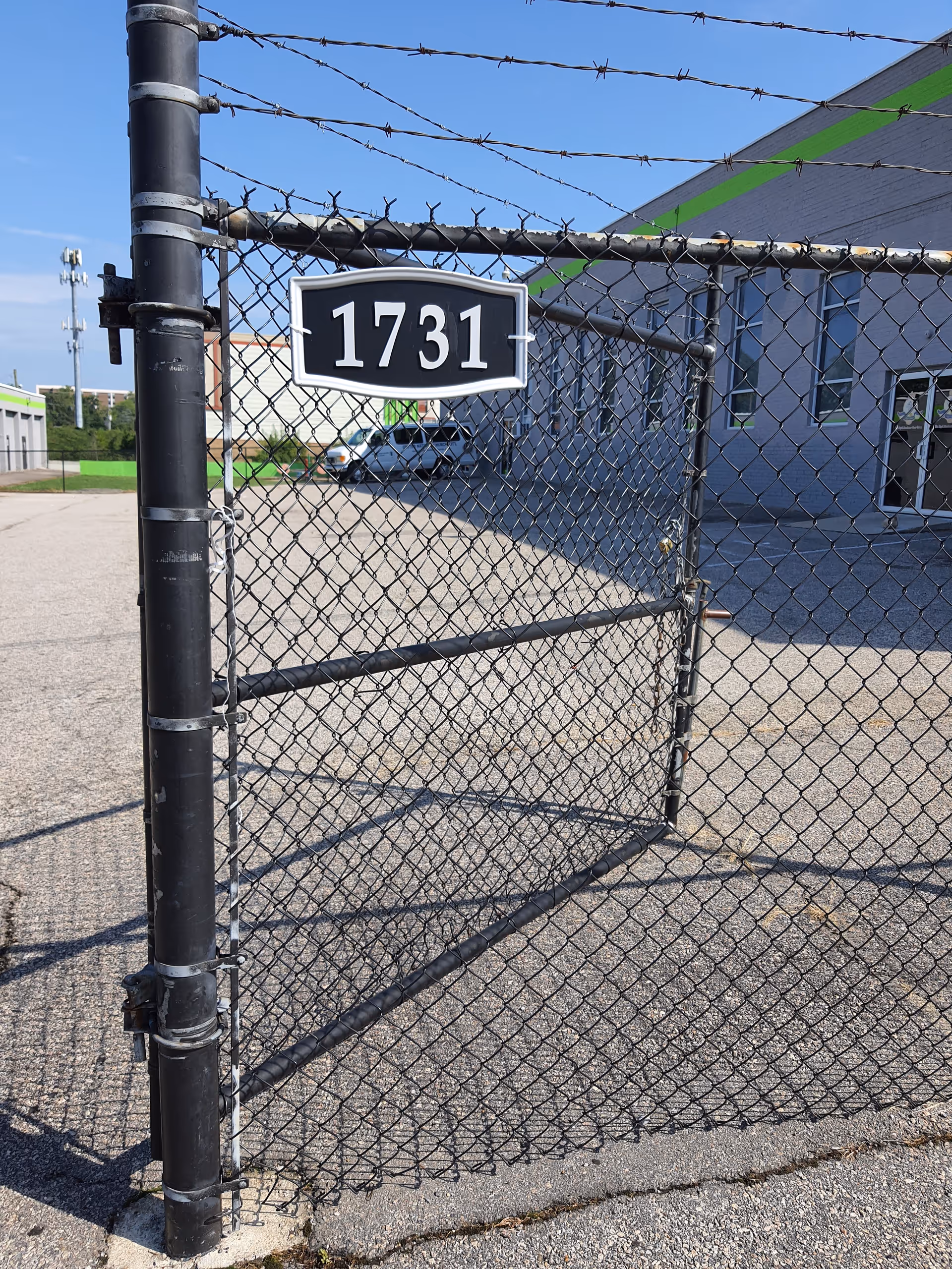 A chain-link gate with the address 1731 blocks view of a gray building exterior.