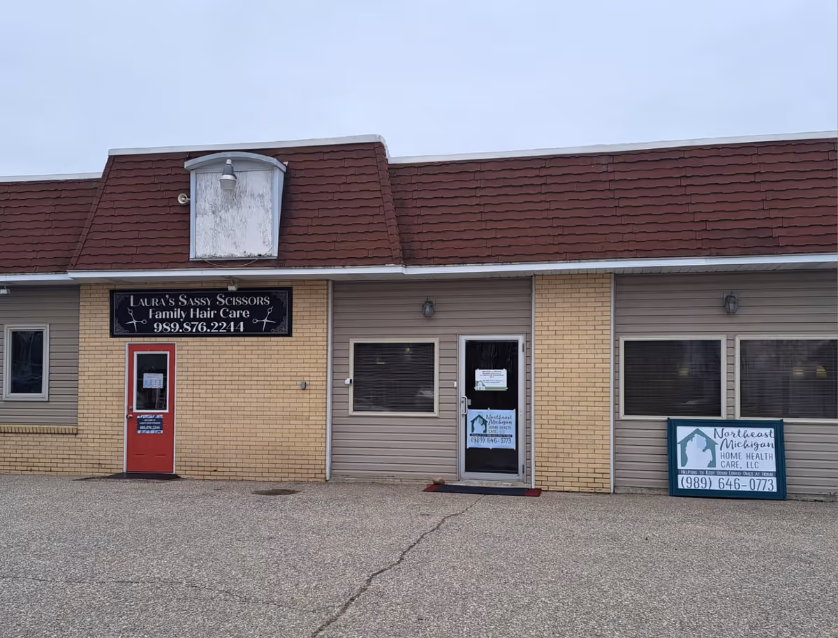 Exterior of a strip storefront with multiple business signs and a red-tiled roof.