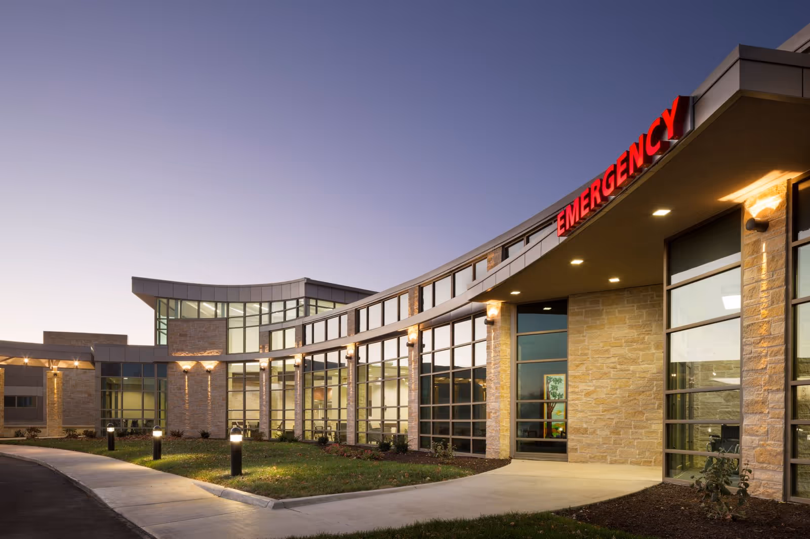 Exterior view of a Community HealthCare System building with curved glass entrance and Emergency sign.