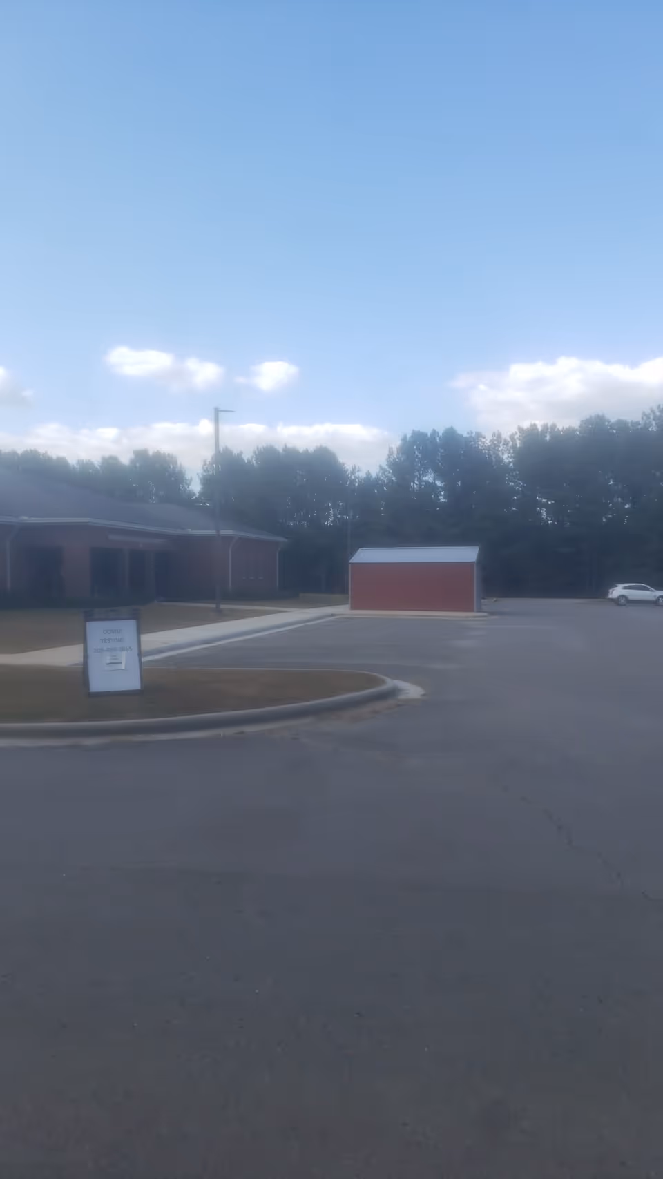 Exterior view of a building with a small red shed in a parking lot.