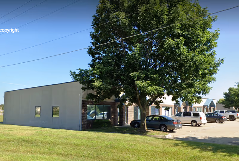 Exterior view of Caring Hearts Home Care building with parking lot and trees.