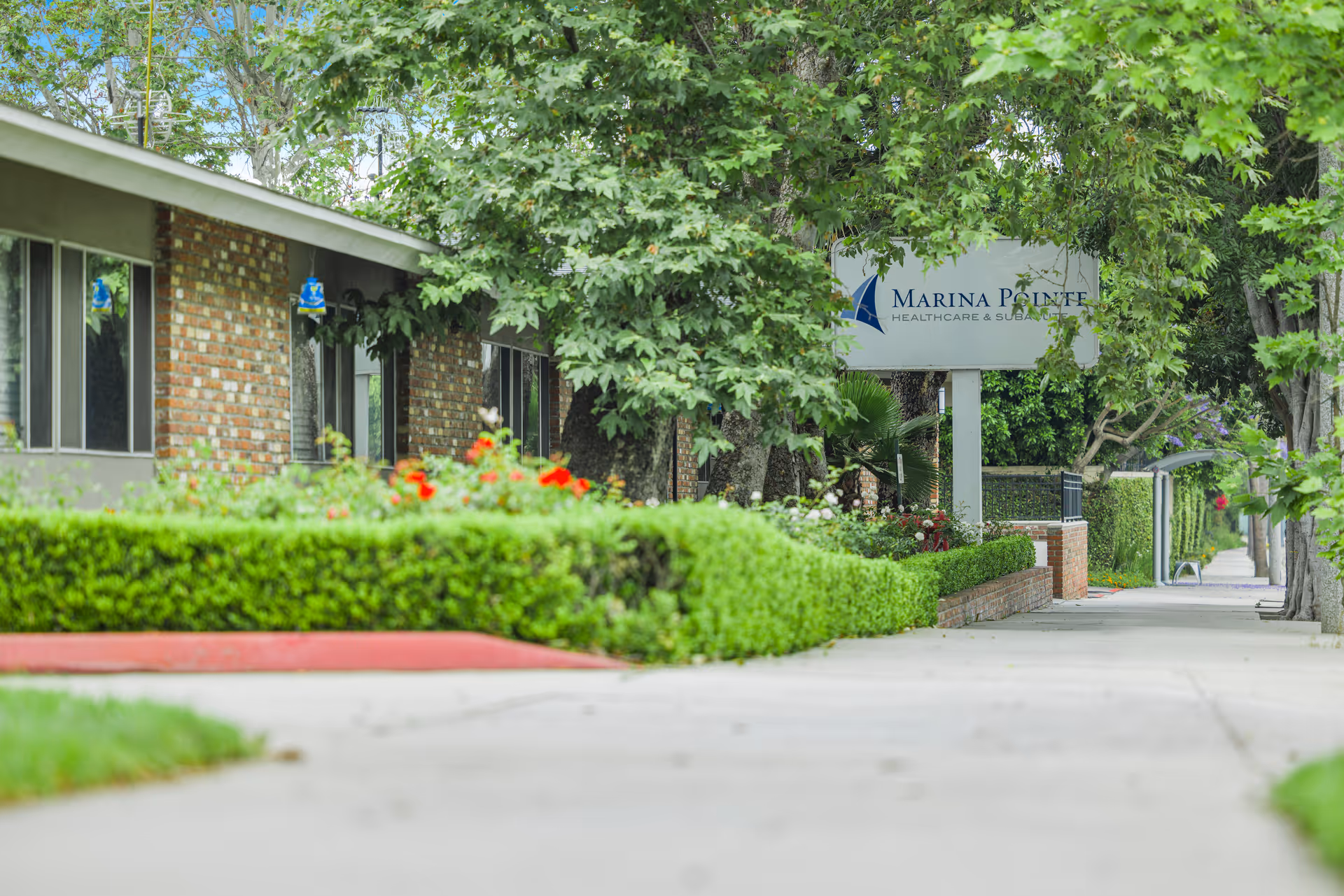 Exterior view of Marina Pointe Healthcare and Subacute with sign and landscaping.