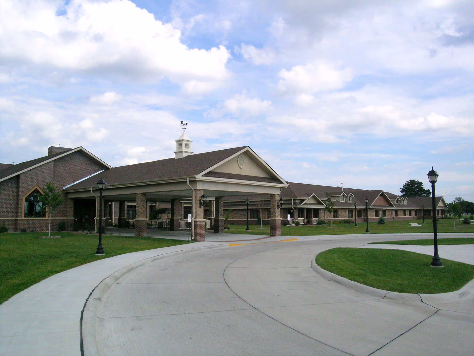 Exterior view of York General Hearthstone: curved driveway, porte-cochere entrance, and low brick building.
