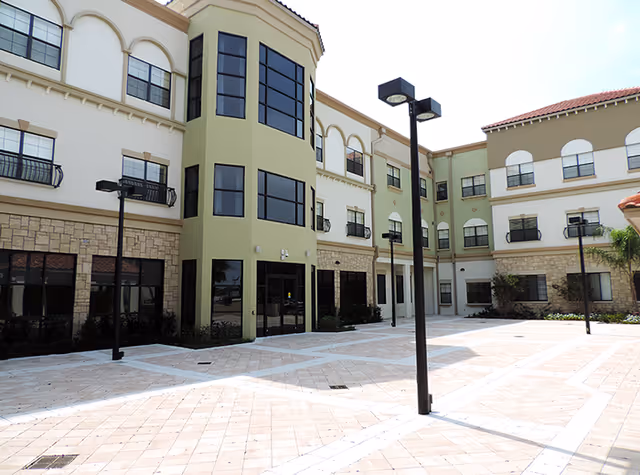 Exterior view of a senior living facility courtyard with modern buildings and lampposts.