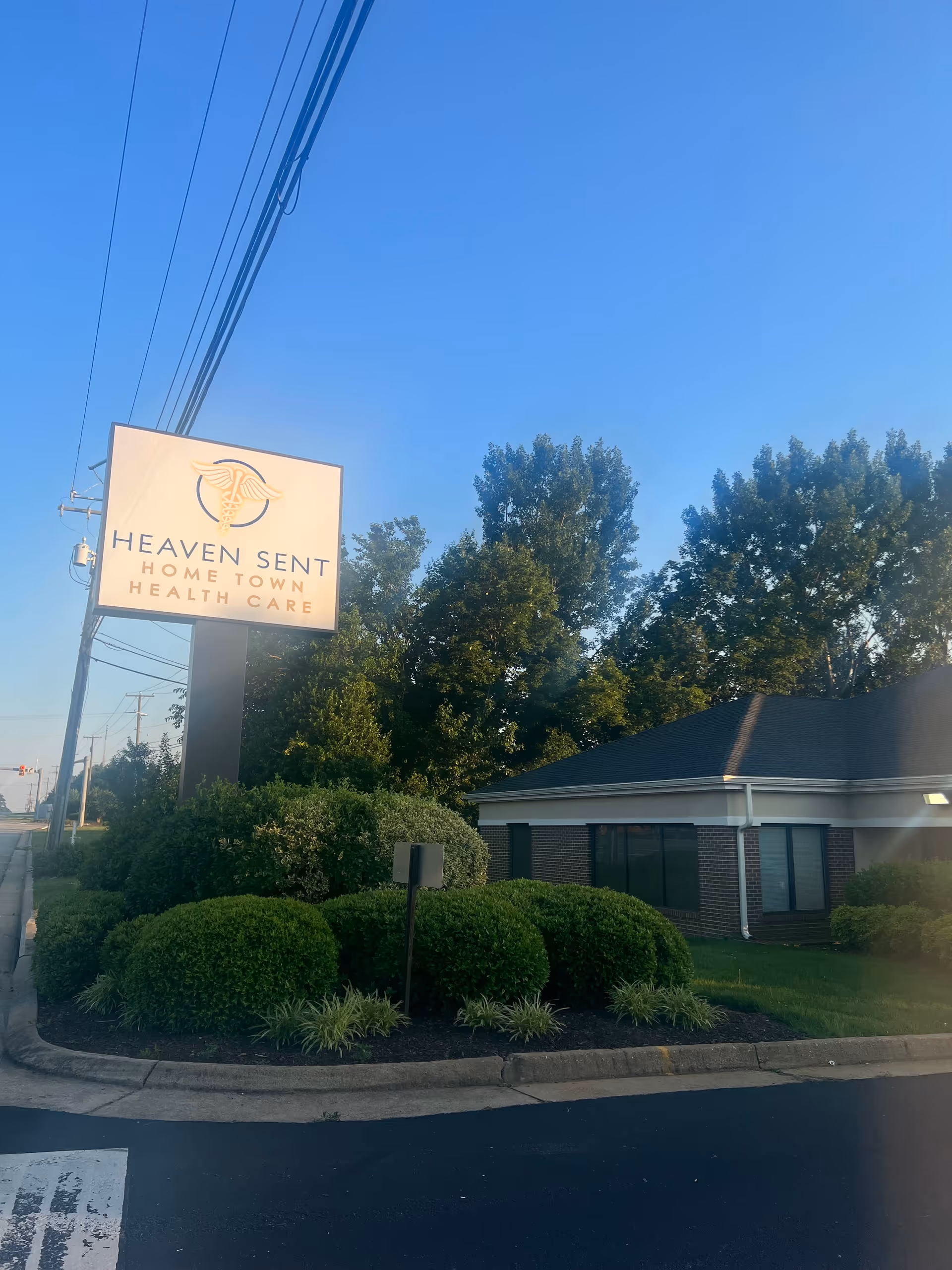 Exterior view of Heaven Sent Home Town Health Care sign beside shrubs and the building.