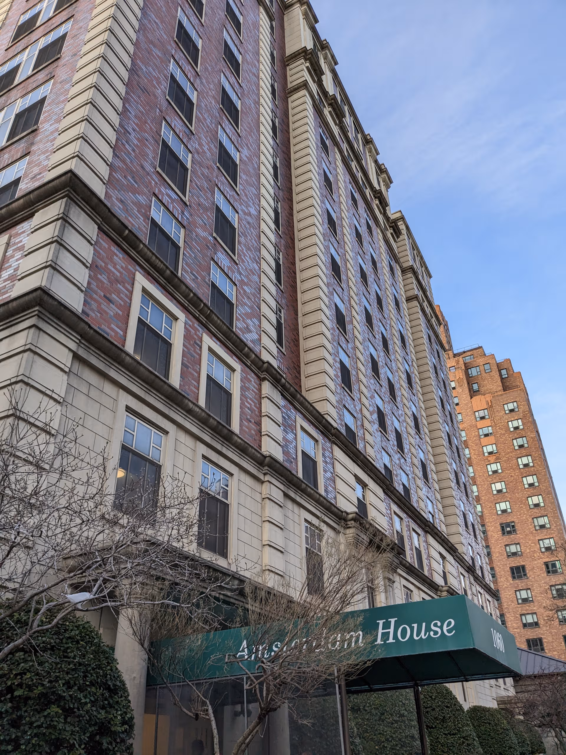 Exterior view of Amsterdam Nursing Home, a tall brick building with a green entrance canopy.