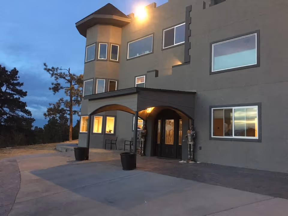 Castle in the Pines Retreat exterior: multi-story building with a curved entry arch at dusk.