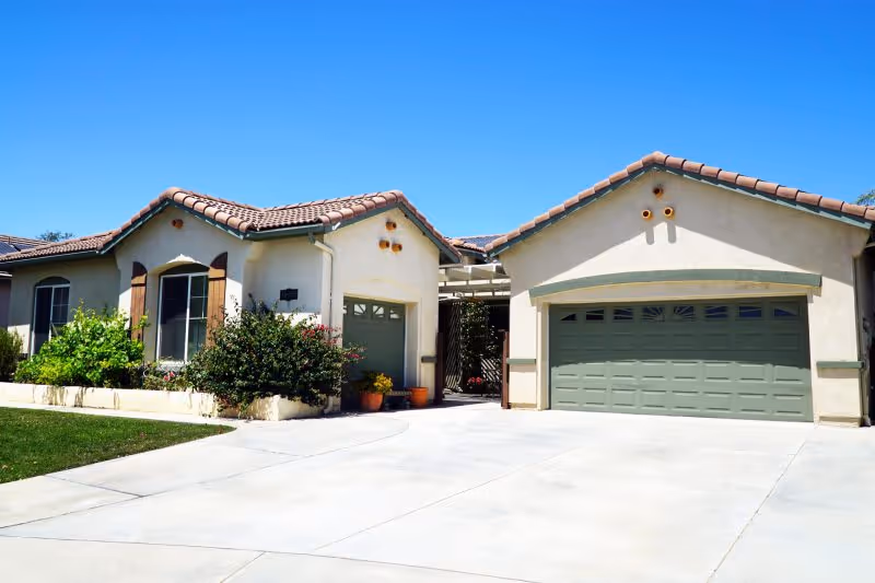 Front exterior view of a single-story home with two garages and landscaping