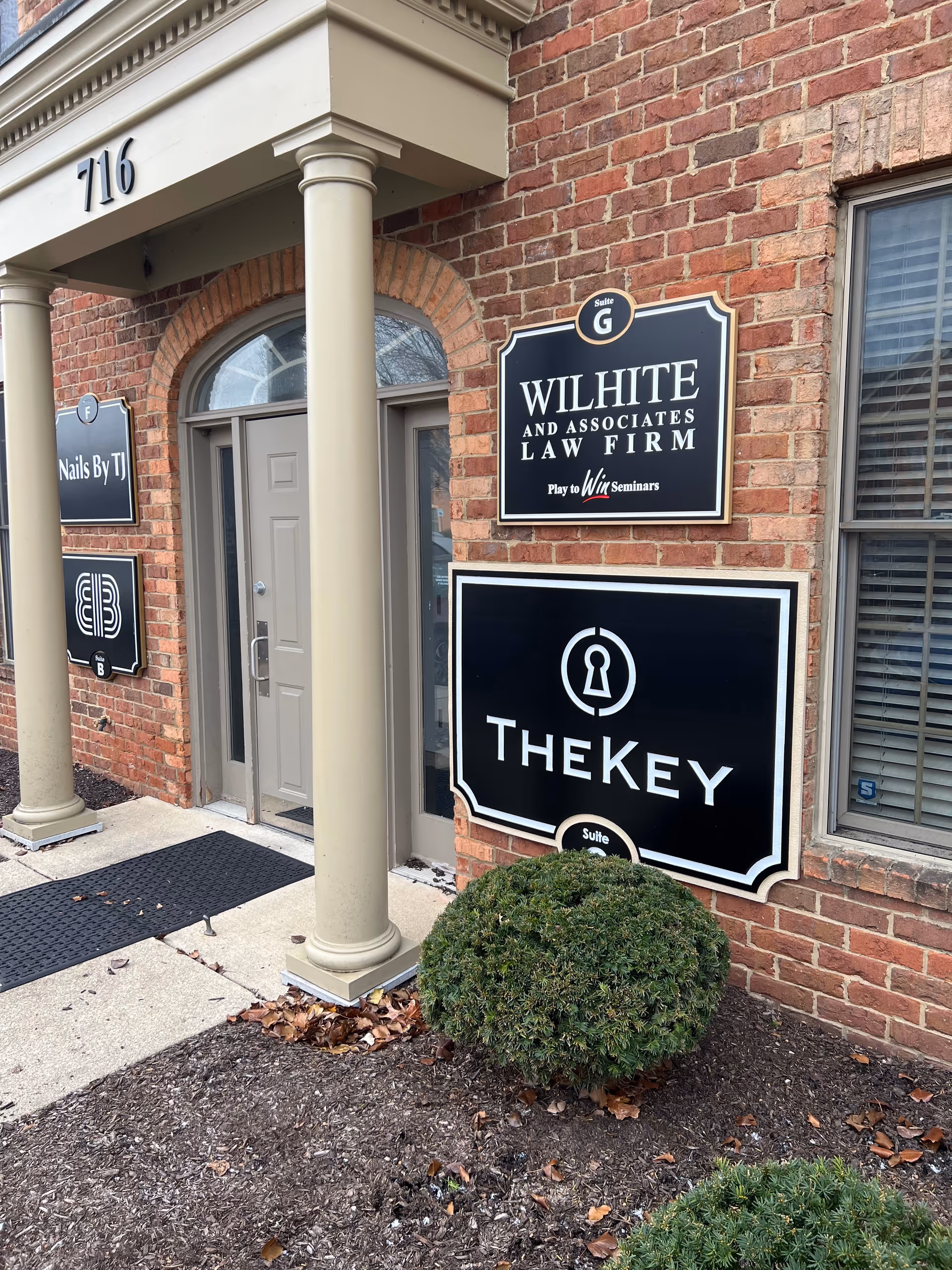 Brick building front with columns, doorway, and a prominent TheKey sign.
