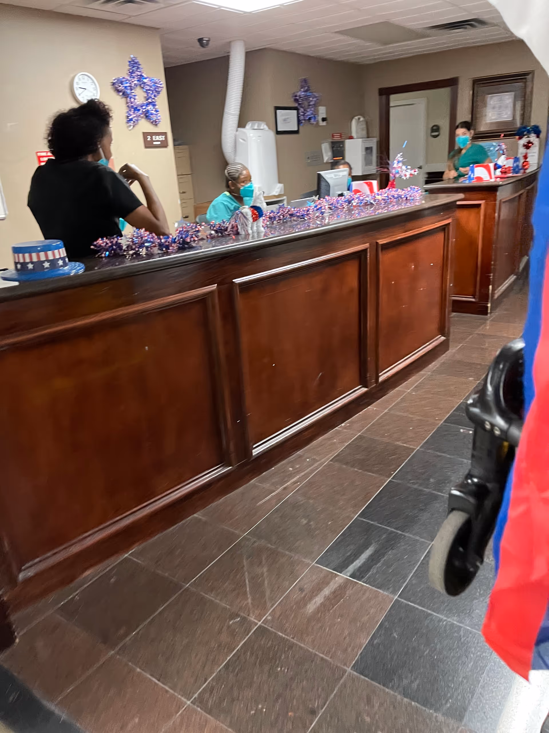 Senior care facility reception area with masked staff at a wooden curved counter.