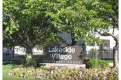 Lakeside Village Apartments entrance sign with landscaped garden and trees.