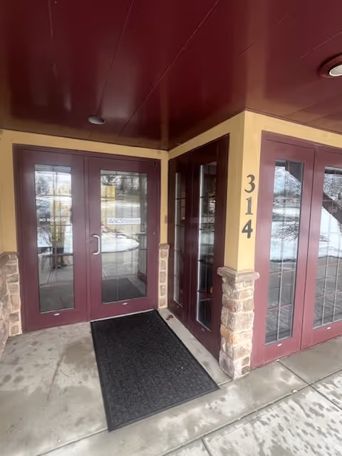 Entrance to ACS Homecare facility with glass doors, maroon frames, and the number 314.