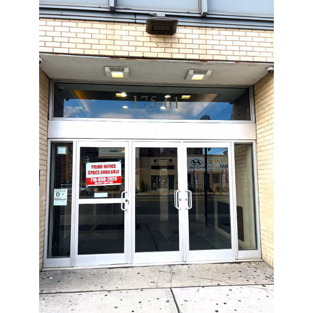 Front entrance with glass doors, brick facade, and reflections of the street.
