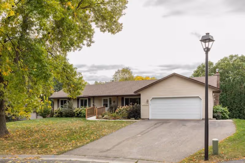 Single-story senior living facility with attached garage and driveway on a tree-lined street.