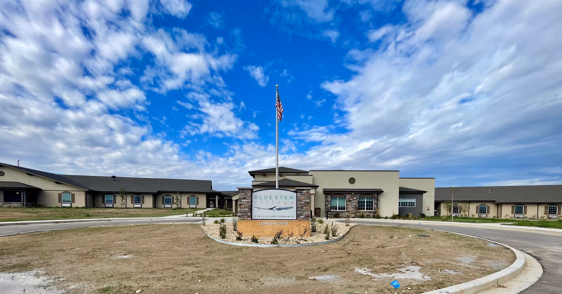 Exterior view of Bluestem Village senior living facility with circular driveway and sign