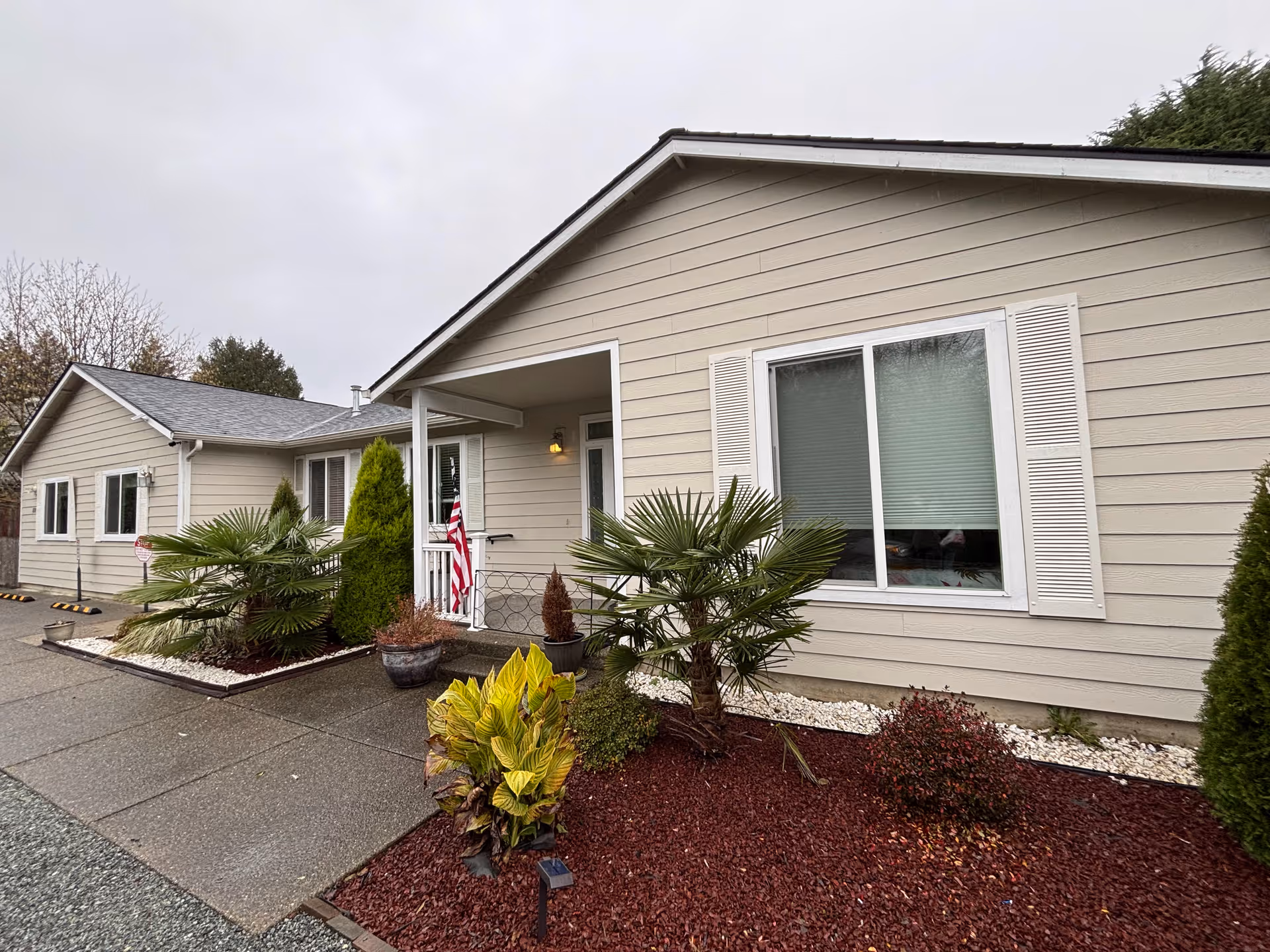 Single-story beige facility exterior with front entrance and landscaped plants.