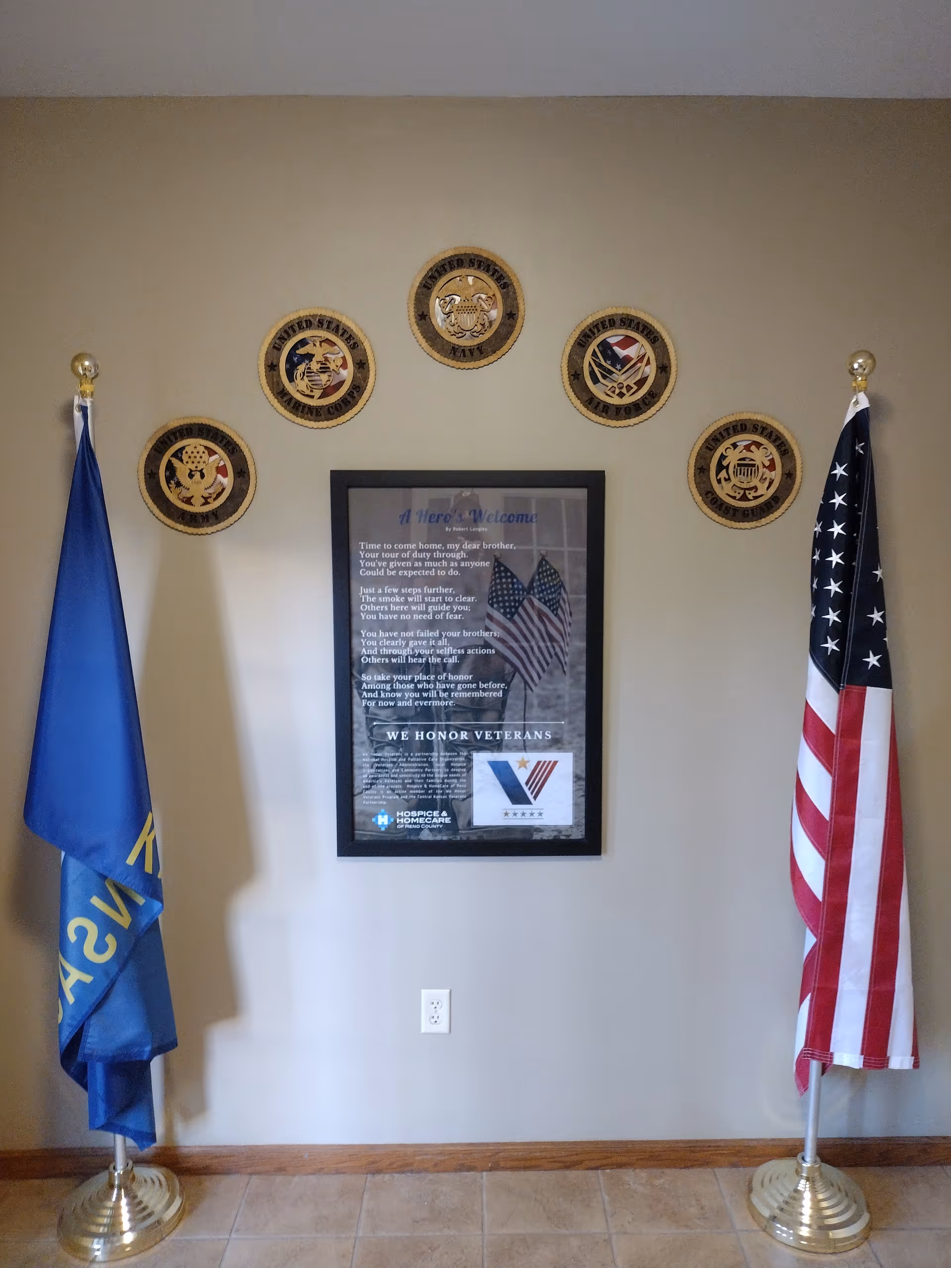 Interior wall with two flags, circular seals, and a framed veterans poster.