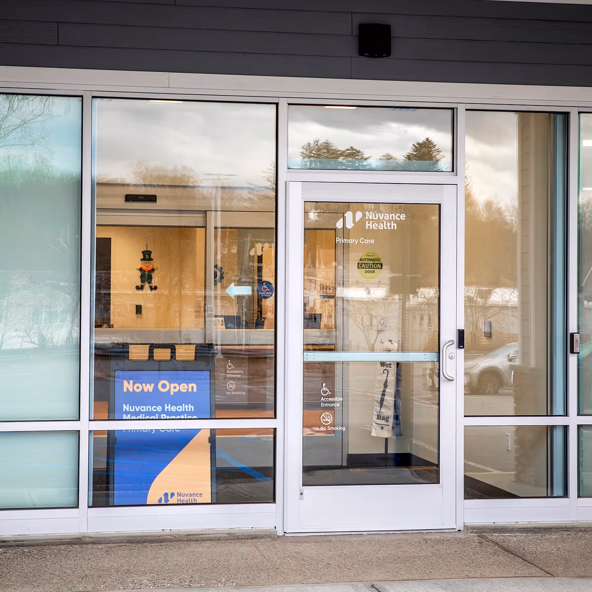 Glass front entrance of Nuvance Health Primary Care Mahopac with Now Open sign.