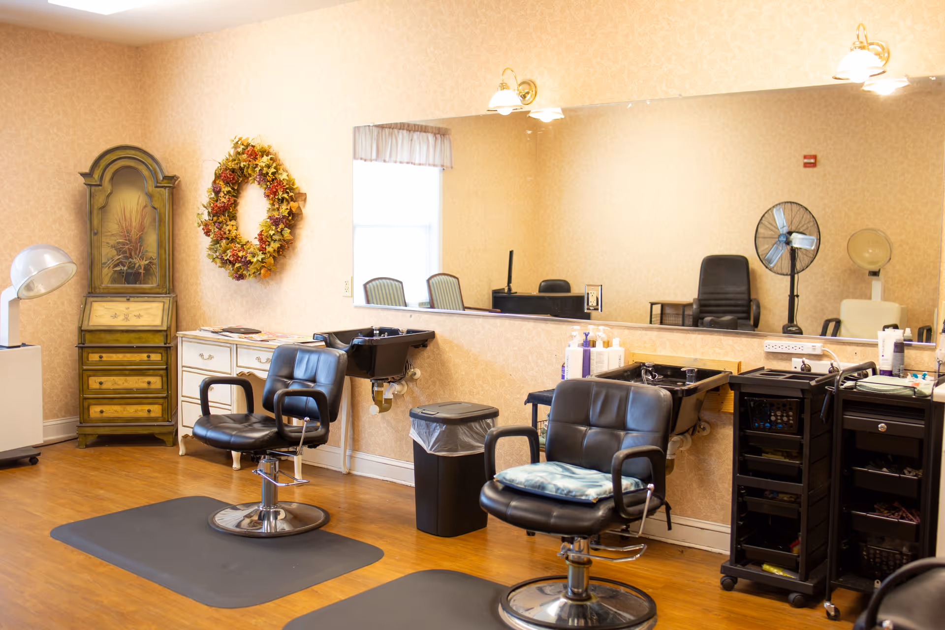 A senior living facility hair salon with styling chairs, a large mirror, and equipment.