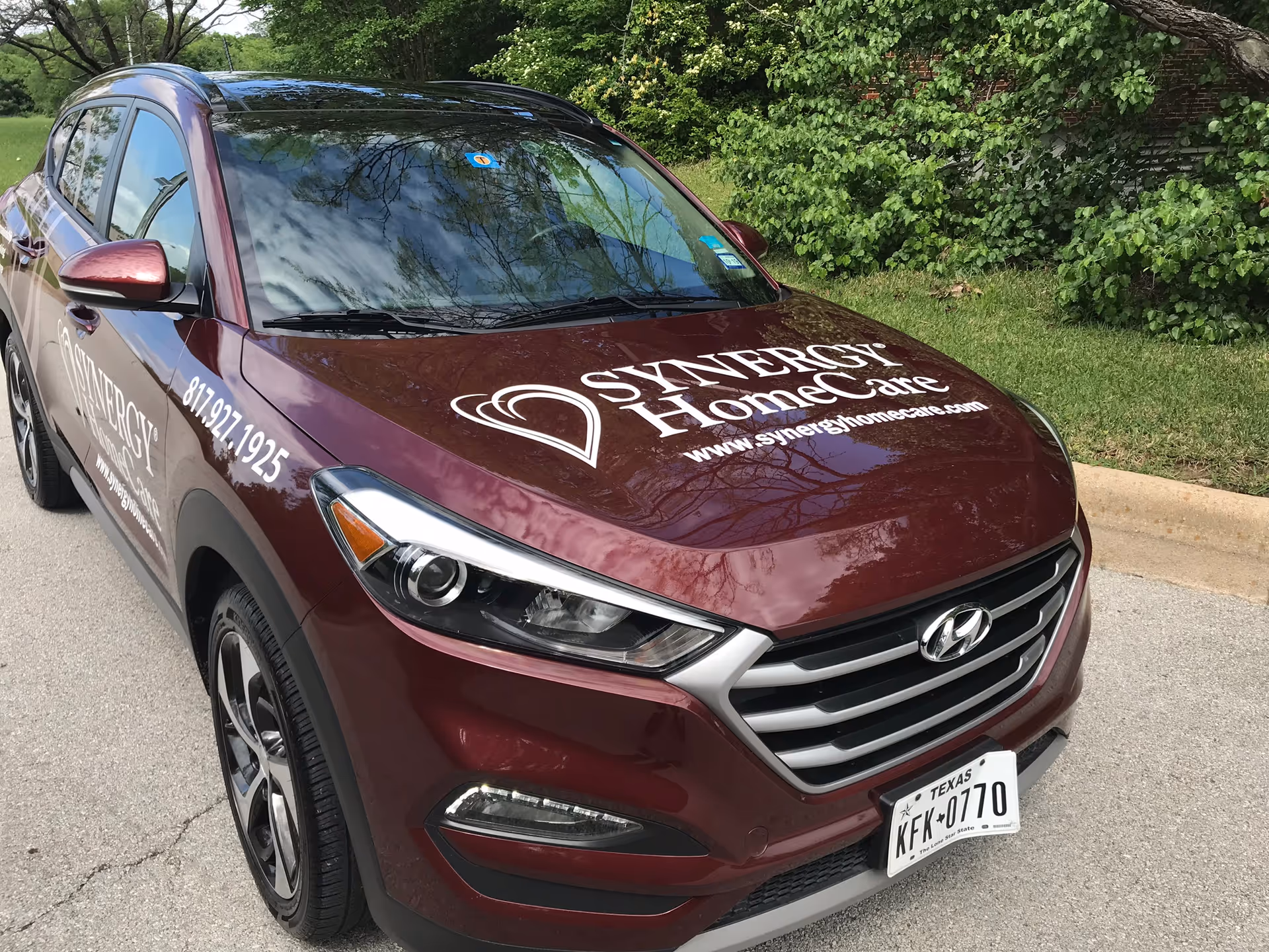 Maroon Hyundai SUV parked outdoors displaying Synergy HomeCare Fort Worth branding on hood and side.
