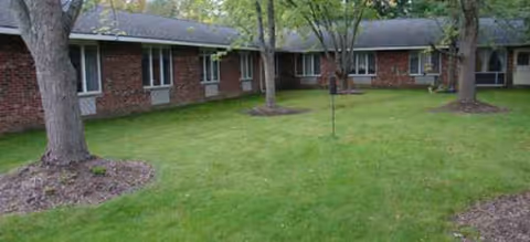 Exterior view of Brookdale East Side senior living building with lawn and trees.