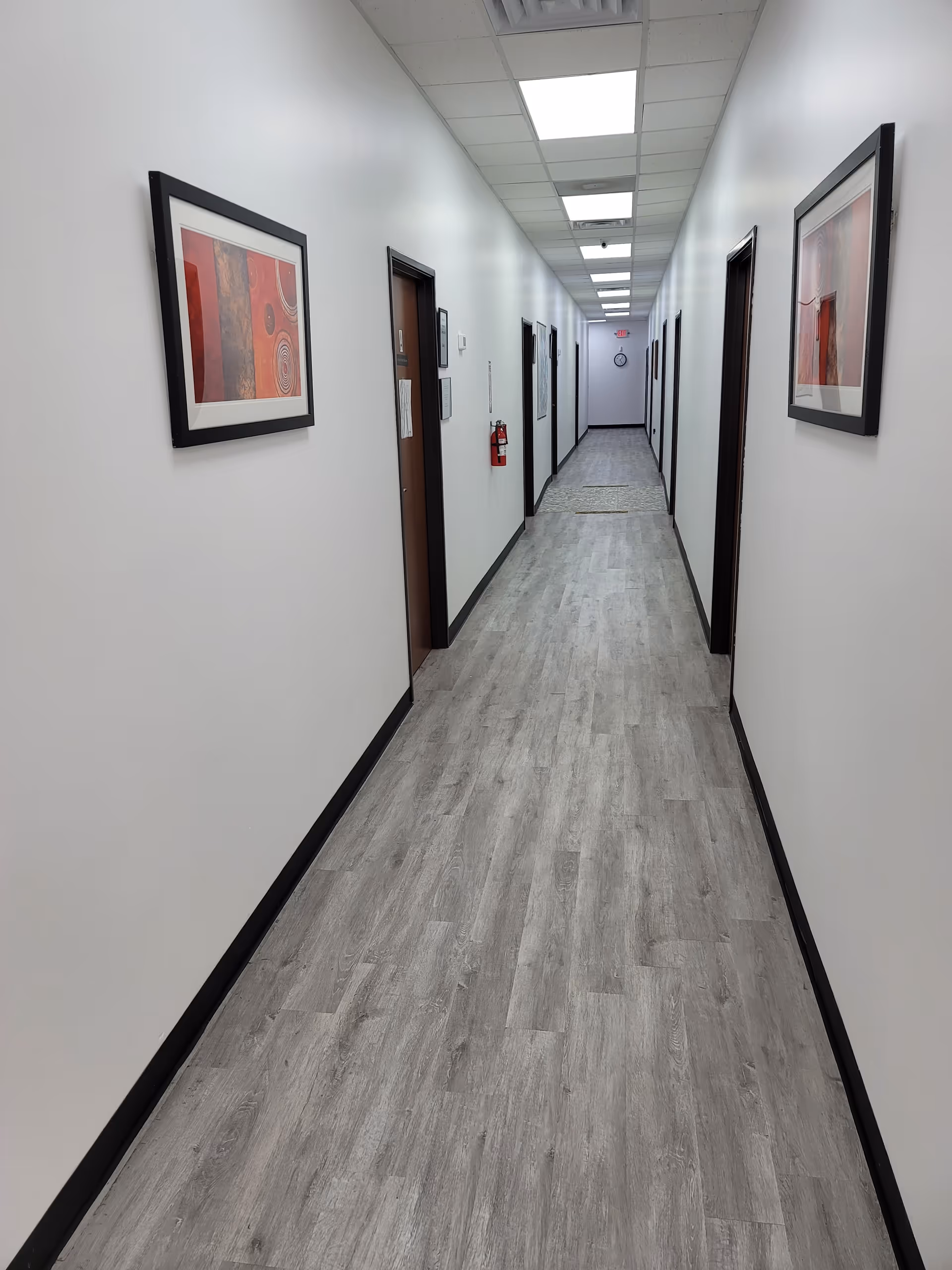 Long, well-lit hallway in a senior living facility with framed art along white walls.