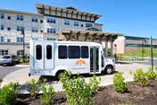 Exterior view of Covenant Village facility with a white bus parked at the entrance