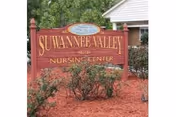 Red Suwannee Valley Nursing Center sign in front of a brick building with shrubs and mulch.