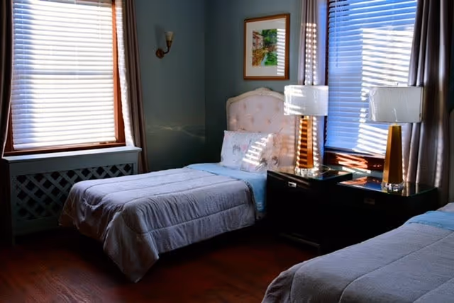 Two twin beds with lamps and nightstands flank a bright seniors' bedroom.