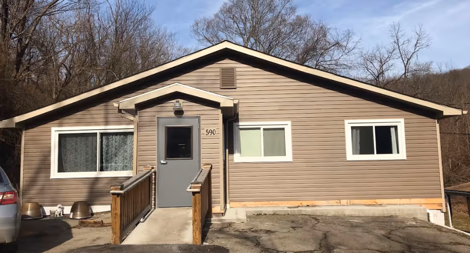 Front view of a single-story brown facility with ramp and two windows.