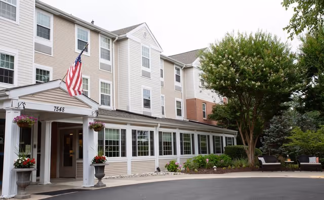 Exterior view of a senior living facility with a welcoming entrance and seating area.