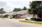 Asbury Towers Retirement Community exterior: single-story building with garages, driveways, and landscaped front yards.