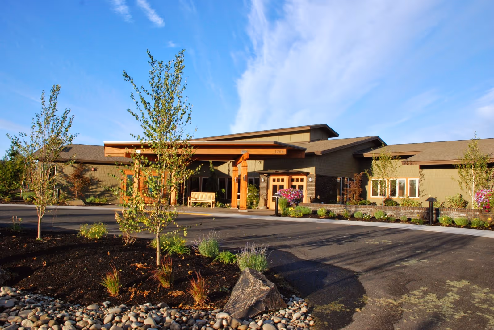 Exterior view of a single-story senior living facility with a covered entrance and landscaping.