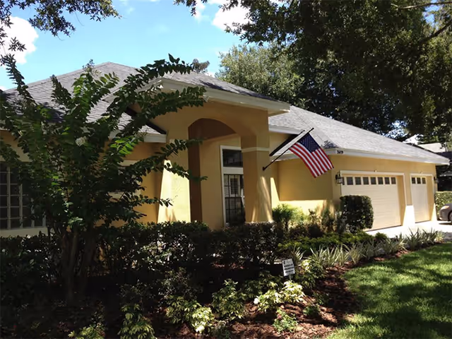 Single-story yellow facility exterior with manicured landscaping and an American flag