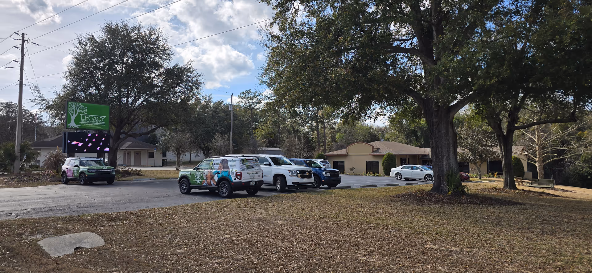Exterior view of Legacy Home Health Care facility with parking lot and trees.