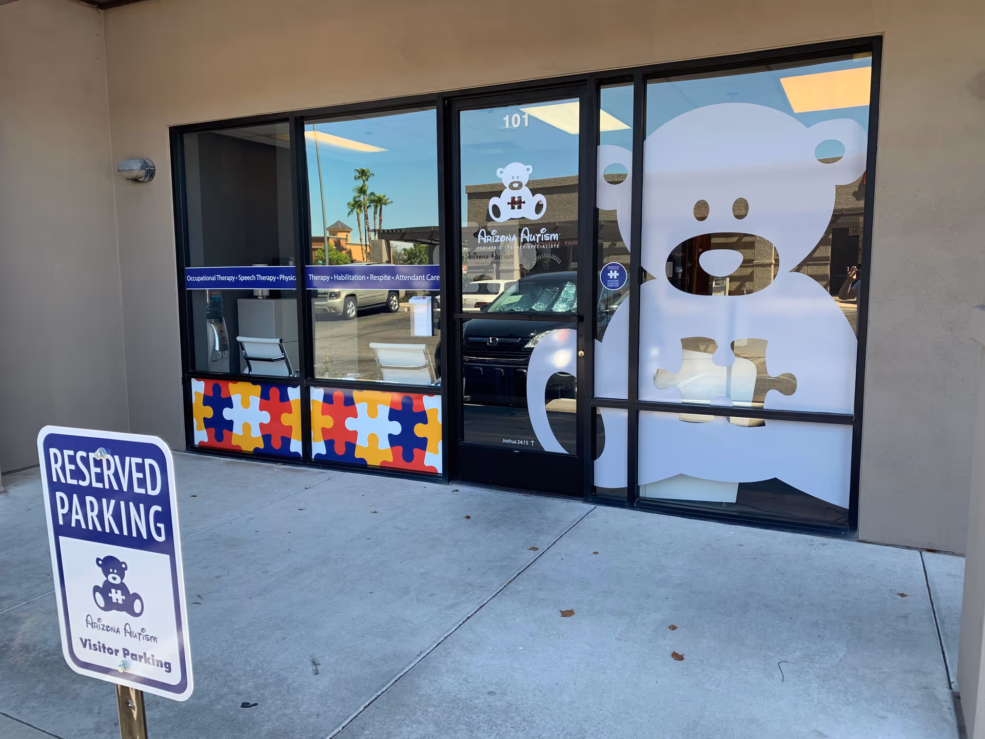 Exterior view of Arizona Autism facility entrance with large window decals and reserved parking sign